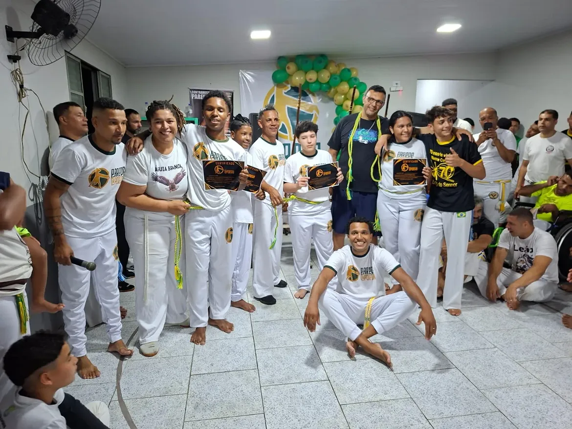 Graduados e alunos com certificados e cordões em evento do grupo